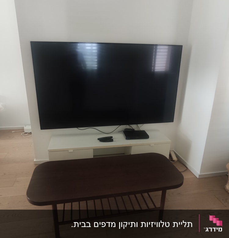 טלוויזיה גדולה על קיר עם כבלים חשמליים